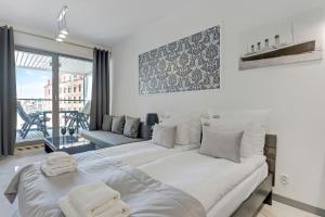 a white bedroom with a large bed and a couch at Downtown Apartments Riverside Granaria in Gdańsk