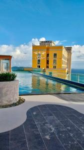 a yellow building with a swimming pool next to the ocean at Emely Lucky Apartment Phu Quoc in Phú Quốc