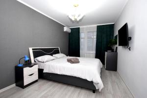 um quarto com uma cama com lençóis brancos e cortinas verdes em Apartmentrent em Chişinău