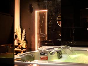 ein Bad mit einem Waschbecken und einem Spiegel in der Unterkunft Douceur du Charme - Love-room à Charmes entre Epinal et nancy in Charmes