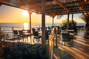 Un patio con mesas y sillas y el mar. en Les villas de Bagheera, oasis naturiste, en Linguizzetta