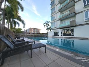 a swimming pool with two chairs next to a building at D'Getaway - Kuching Prime Area - Family Oasis - Spacious Condo in Kuching