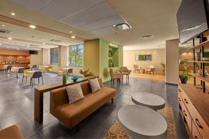 a waiting room with a couch and tables and chairs at City Express Plus by Marriott Cabo San Lucas in Cabo San Lucas