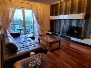 a living room with a leather couch and a television at D'Getaway - Kuching Prime Area - Family Oasis - Spacious Condo in Kuching