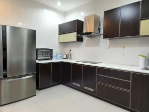 a kitchen with brown cabinets and a stainless steel refrigerator at D'Getaway - Kuching Prime Area - Family Oasis - Spacious Condo in Kuching