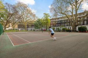 a man playing tennis on a tennis court at Russell Square Vintage - 2 Cozy Bed Home in London