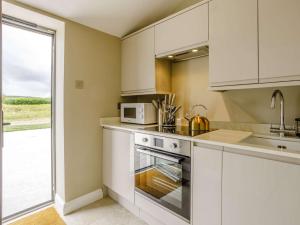 uma cozinha com armários brancos e um micro-ondas em 1 bed property in Huntingdon 83312 em Sawtry