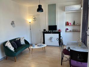 uma sala de estar com um sofá verde e uma mesa em Appartement Climatisé La Gallinette em Perpignan