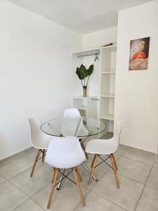 una mesa de comedor de cristal con sillas blancas en Departamento nuevo Solar Ameghino con COCHERA costo aparte en Resistencia