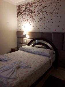 a bedroom with a bed with a tree on the wall at LOFT NOVO CONFORTÁVEL in Sorocaba