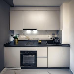 una cocina con armarios blancos y horno negro en Central Luxury Home, en Timisoara