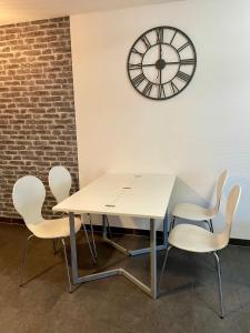 einen weißen Tisch und Stühle mit einer Uhr an der Wand in der Unterkunft Le T2 Appartement Moderne avec Terrasse et Parking in Straßburg