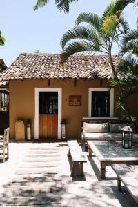 une maison avec une table et des bancs devant elle dans l'établissement Casa La Torre Hotel Boutique, à Trancoso