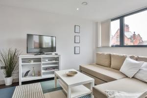 a white living room with a couch and a tv at Apartments in Sheffield in Sheffield