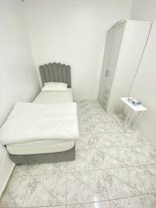 a bedroom with a bed and a cabinet and a tiled floor at Single bed hosted by dinar apartments in Abu Dhabi