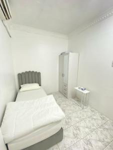 a white room with a bed and a cabinet at Single bed hosted by dinar apartments in Abu Dhabi