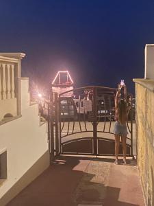 una mujer de pie en un balcón tomando una foto de la noche en B&B Santa Maria Di Leuca, en Leuca