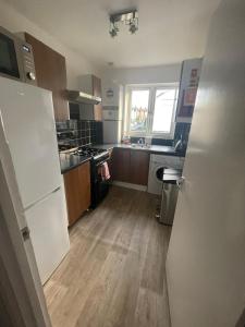 a kitchen with a white refrigerator and a wooden floor at Spacious 3 Bed Flat in Greenwich in London