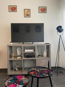 a living room with a flat screen tv and a stool at LE POP ART Studio-Proche tram in Gaillard