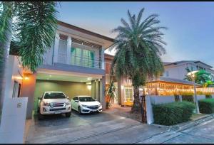 dos coches aparcados frente a una casa con palmeras en พลูวิลล่า villa pattay en Ban Rong Po