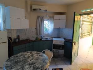 une cuisine avec des placards verts, une table et une fenêtre dans l'établissement Mare e Monti1, à Kamena Vourla