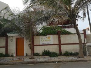 un panneau sur le côté d'un bâtiment avec des palmiers dans l'établissement Auberge Keur Diame, à Dakar