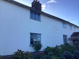 a white house with two windows on the side of it at Black Sheep Cottage in Saxmundham