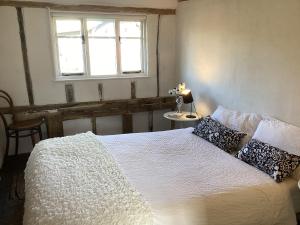 a bedroom with a white bed with pillows and a window at Black Sheep Cottage in Saxmundham