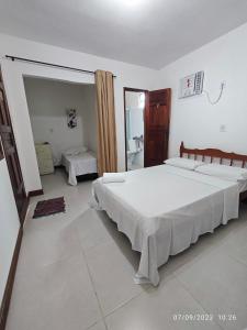 a large bedroom with two beds and a mirror at Pousada Villa Graciela in Ilhéus