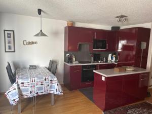 a kitchen with red cabinets and a table in it at Apartmenthaus Majesta in Leukerbad