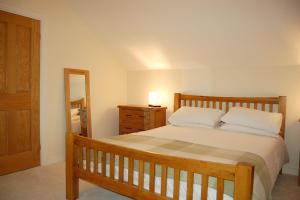 a bedroom with a bed and a dresser and a mirror at Anneddle Cottage in Talybont, near Barmouth in Talybont