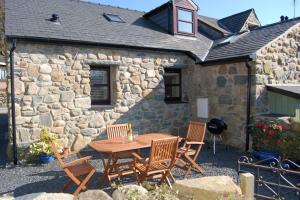 a table and chairs in front of a stone building at Anneddle Cottage in Talybont, near Barmouth in Talybont
