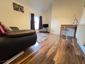 a living room with a black couch and a wooden floor at Double Room Near City Centre With Extra Lounge Area in Preston