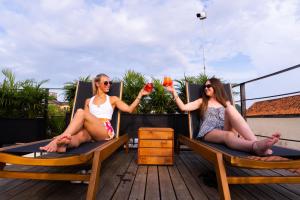 dos mujeres sentadas en sillas en una terraza con bebidas en Los Patios Hostel, en Cartagena de Indias