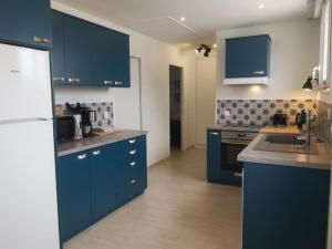 cocina con armarios azules y nevera blanca en APPARTEMENTS- Place Alexandres 4 Vents, en Asnelles