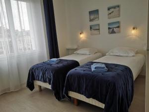 2 camas con sábanas azules en una habitación con ventana en APPARTEMENTS- Place Alexandres 4 Vents, en Asnelles