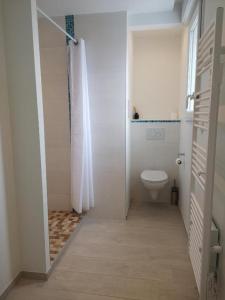 a white bathroom with a toilet and a shower at APPARTEMENTS- Place Alexandres 4 Vents in Asnelles