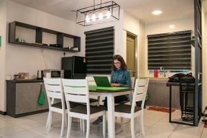 a woman sitting at a table with a laptop at A3A Oastel coLiving in Tanah Rata
