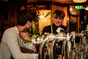 zwei Männer, die an einer Bar sitzen und eine Brille ansehen in der Unterkunft Long John's Pub & Hotel in Amersfoort