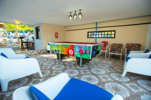 a pool table in a room with white chairs at Rusty Rock Beach Resort & Spa in Mwanza