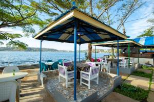 a gazebo with chairs and tables next to the water at Rusty Rock Beach Resort & Spa in Mwanza