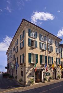 un gran edificio con banderas a un lado en Hotel Garnì Riviera, en Gargnano