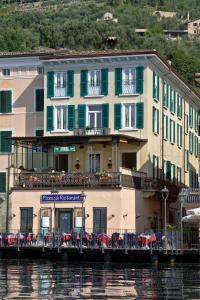 un edificio sobre el agua con mesas y sillas en Hotel Garnì Riviera, en Gargnano
