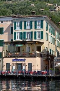 a building on the water with tables and chairs at Hotel Garnì Riviera in Gargnano