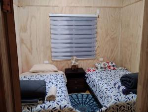 2 camas en una habitación con ventana en Residencial 4 estaciones en Futaleufú