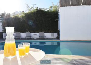 Igrejinha的住宿－MyStay - Casa de Baco，两杯橙汁坐在泳池旁的桌子上