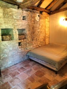 a bedroom with a bed in a stone wall at La Framie basse in Albas