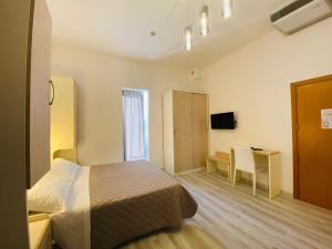 a bedroom with a bed and a desk and a television at Hotel Butterfly Wellness & Spa in Rimini