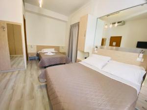 a hotel room with two beds and a large mirror at Hotel Butterfly Wellness & Spa in Rimini
