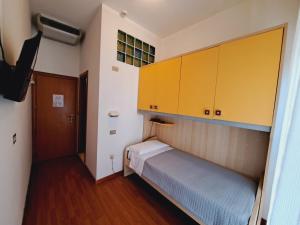 a small room with a bed and yellow cabinets at Hotel Butterfly Wellness & Spa in Rimini
